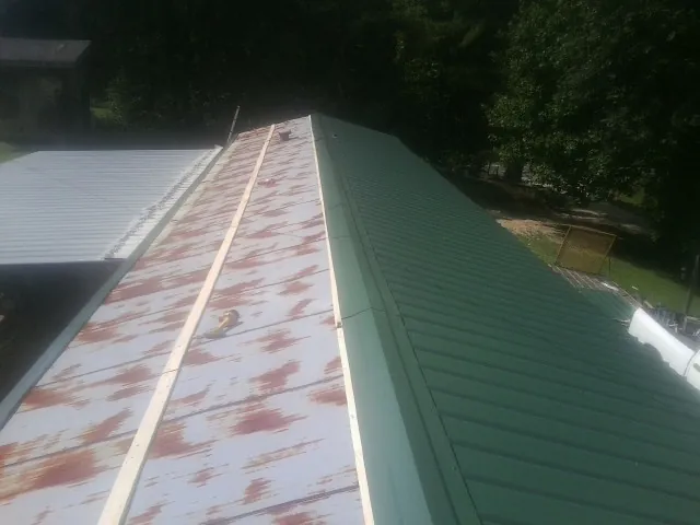 Old rusted panels beside newly installed green metal roofing — Wind Damage Roof Repair by Roofing Brothers in Skyforest
