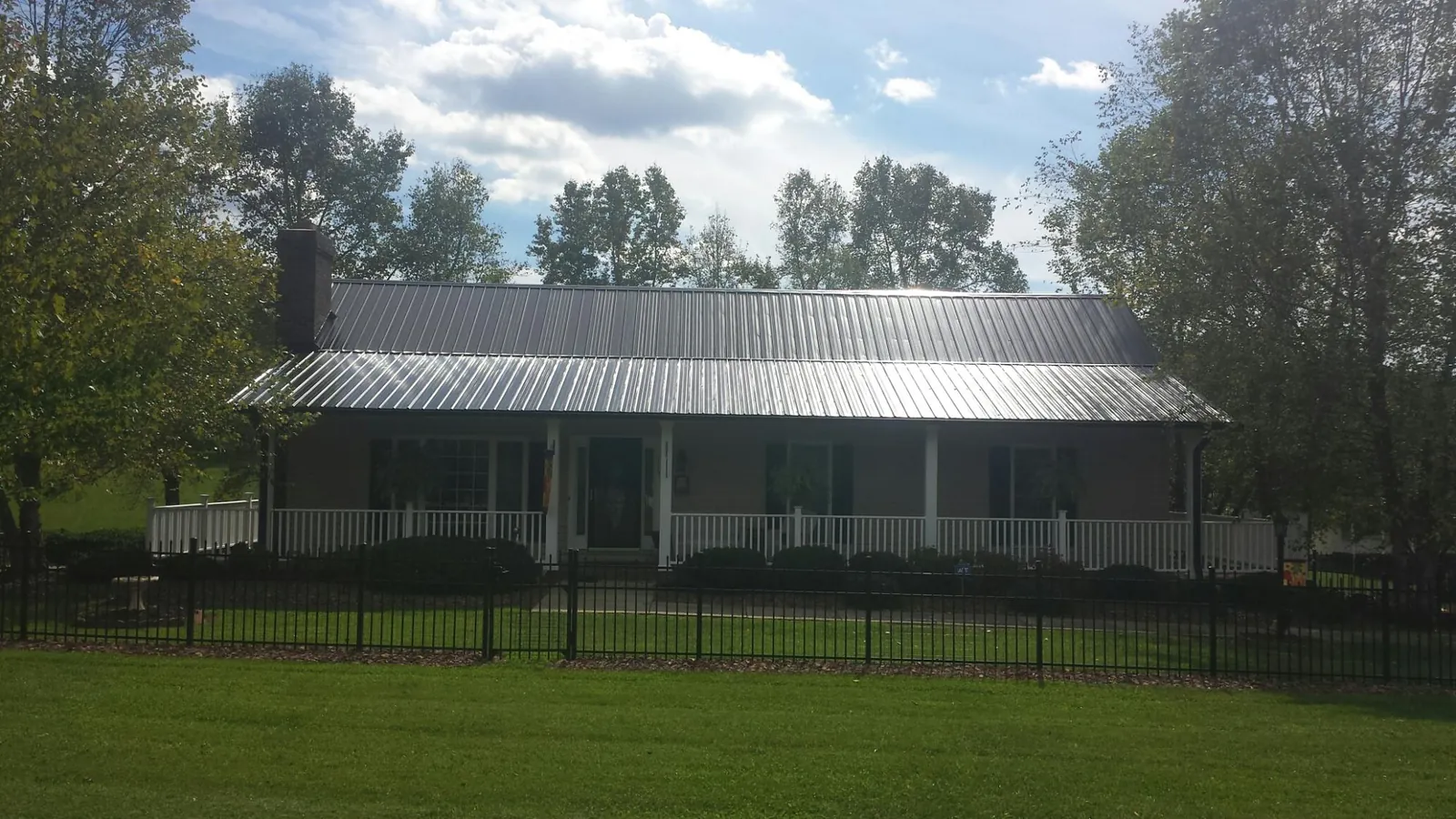 Gray metal roof on a brick ranch with a full width front porch — Gutter Guard Installation work by our crew in Skyforest