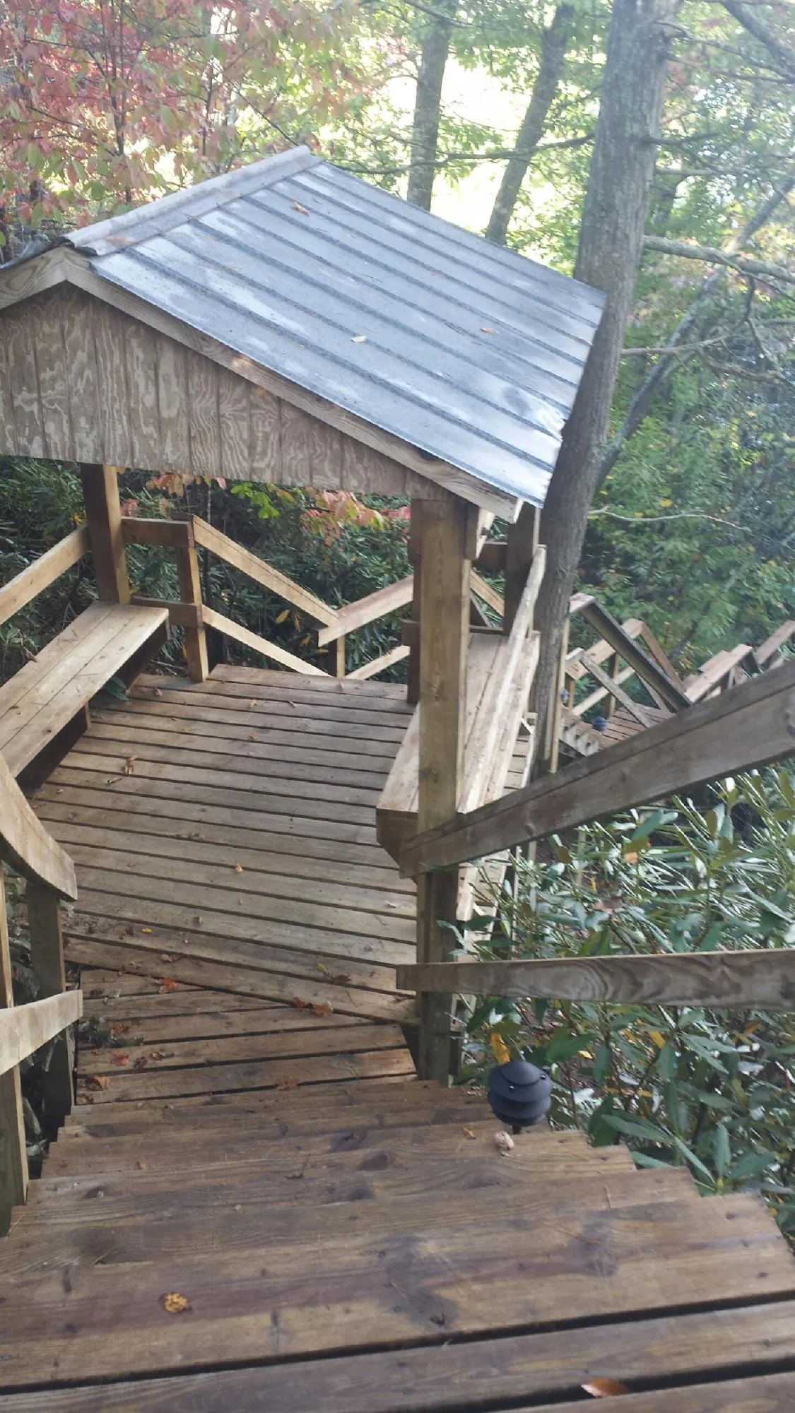 Metal roofed shelter over wooden steps on a wooded walkway — Skylight Repair & Installation work by our crew in Skyforest