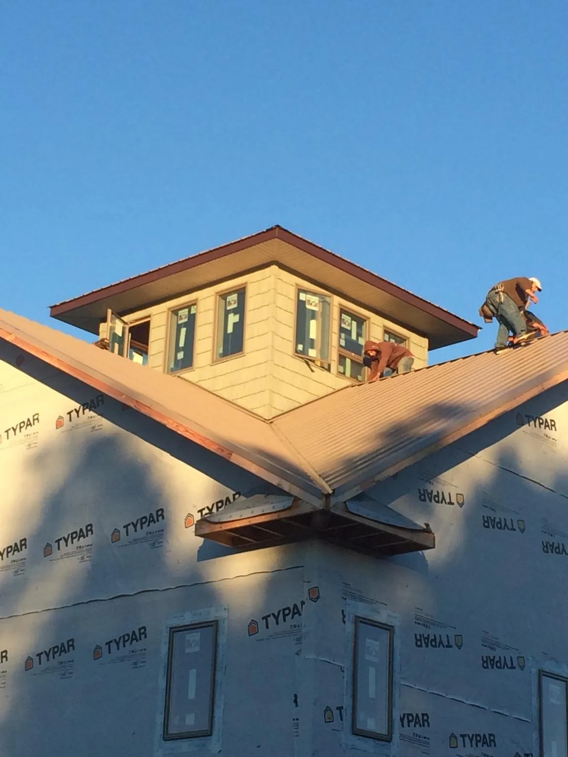 Roofers working around a rooftop cupola on a new metal roof at sunset — Roof Waterproofing in Skyforest by Roofing Brothers
